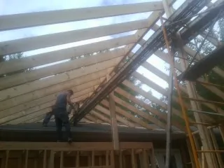 Rafters going up over a new addition with a worker on the wall in Fillmore