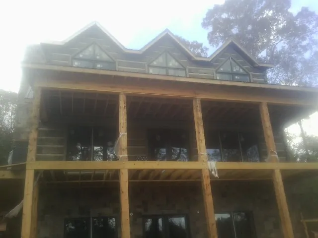 Dormers and porch framing on a large log home under construction — Roof Coating work by our crew in Fillmore